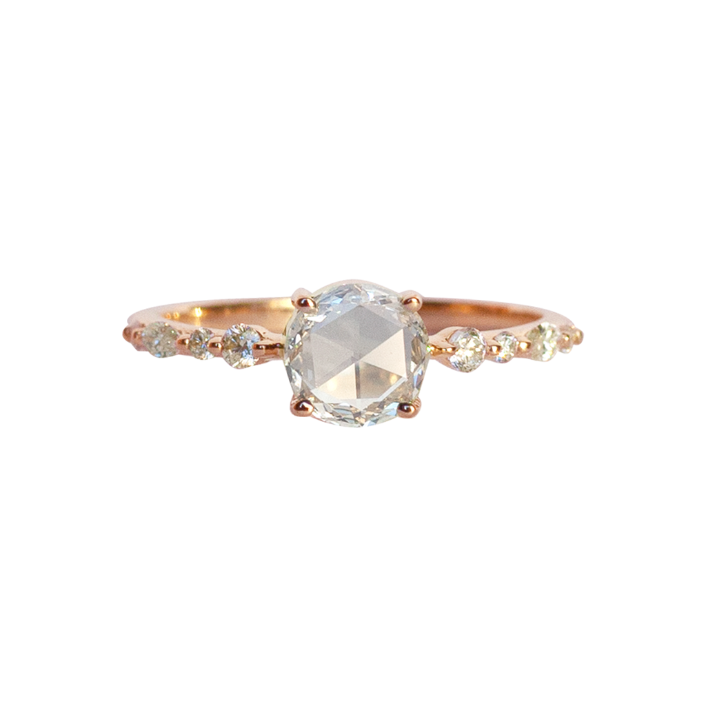 A twist on a classic solitaire engagement ring, featuring a round rose cut diamond, set with four prongs. The main diamond sits on maquise and round brilliant cut diamond band. Made in 14k or 18k rose gold. 