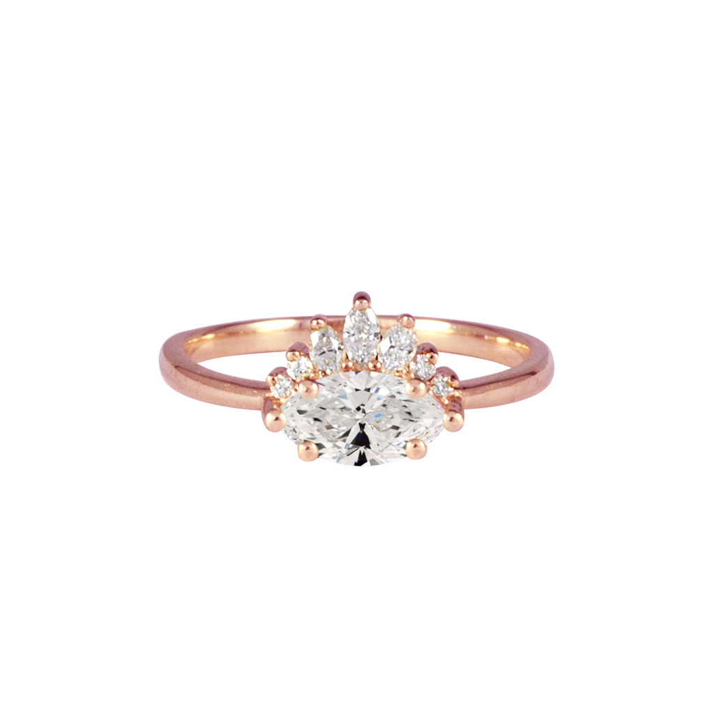 Contemporary take on a traditional marquise diamond ring features an East-West marquise diamond. The centre stone is surrounded with a diamond crown of marquise and round brilliant diamonds. Made in solid 14k or 18K rose gold.