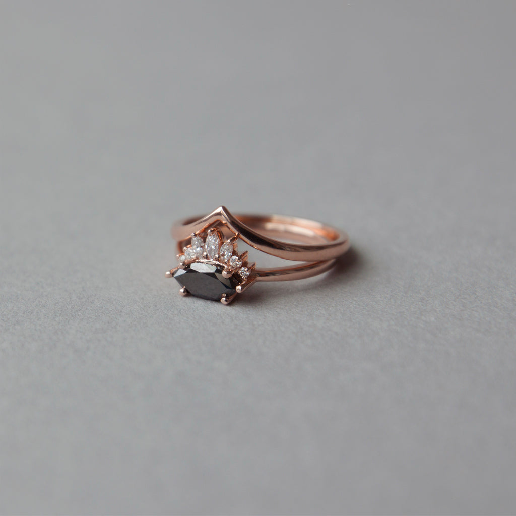 Contemporary take on a traditional marquise diamond ring features an East-West marquise black diamond. The centre stone is surrounded with a diamond crown of marquise and round brilliant diamonds. Made in solid 14k or 18K rose gold. 